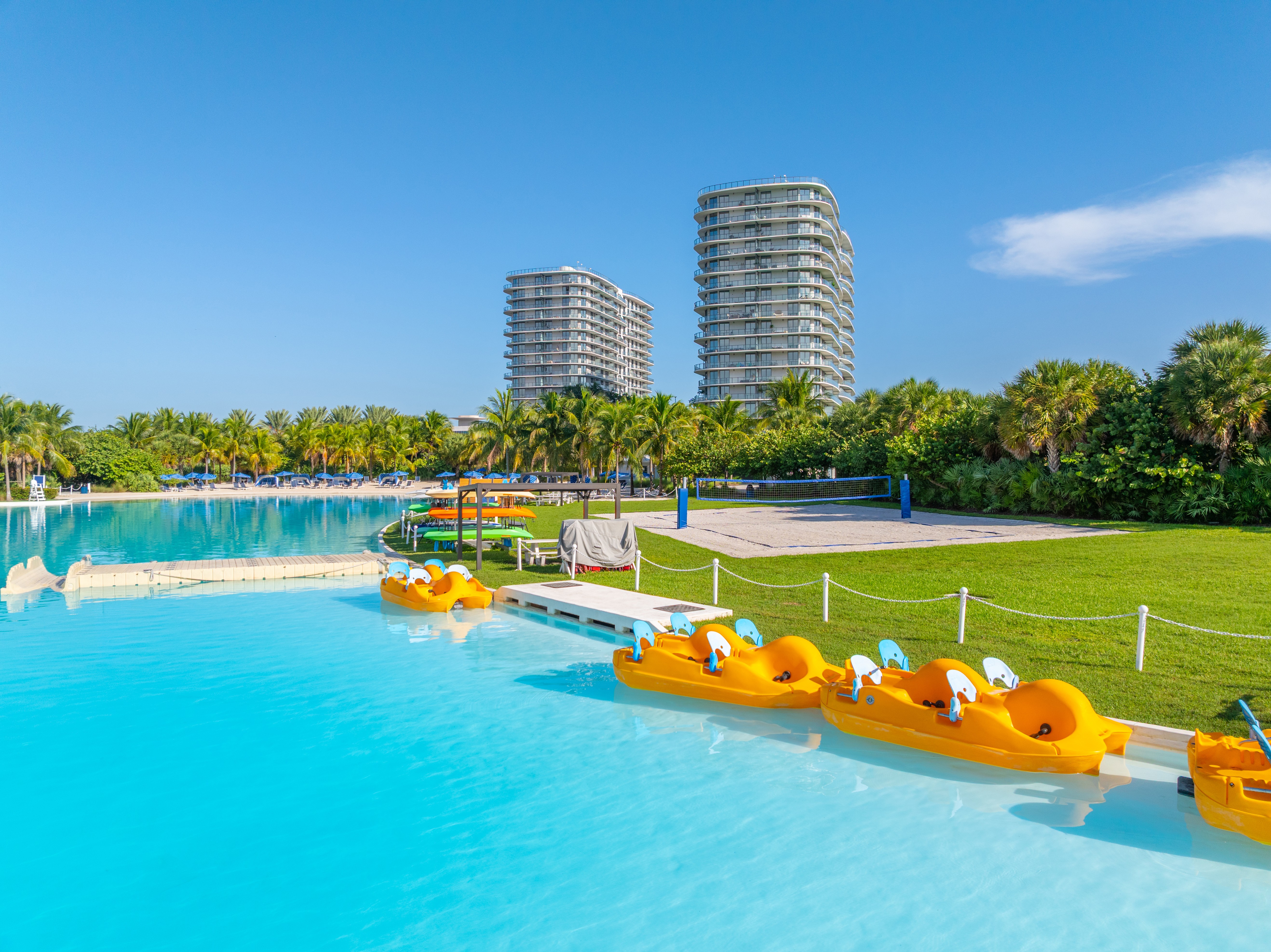 A pool with yellow chairs and palm trees in the background.